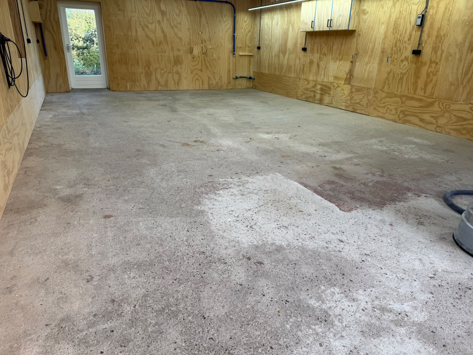 Ruwe betonvloer met hoogteverschillen en verfresten in garage in Spanbroek