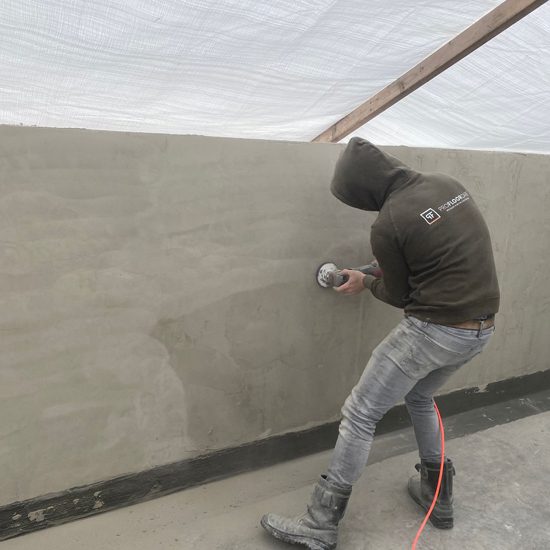 Betonnen zwembadwand schuren in Loosdrecht Medewerker schuurt de betonnen wand van een zwembadbak in Loosdrecht